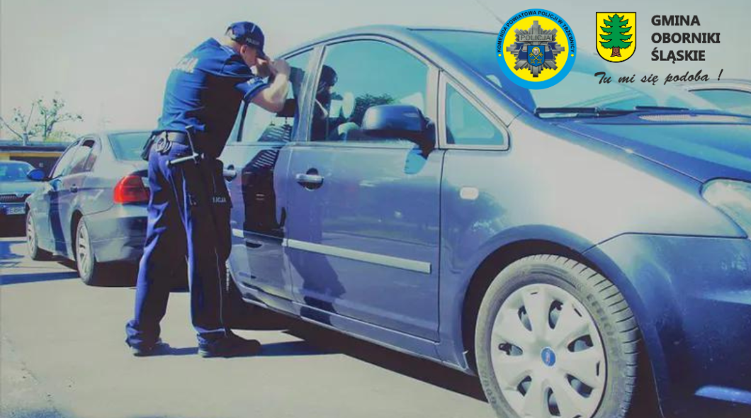 Policjant zaglądający do nagrzanego auta, w którym może znajdować się pozostawione dziecko