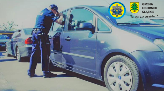 Policjant zaglądający do nagrzanego auta, w którym może znajdować się pozostawione dziecko