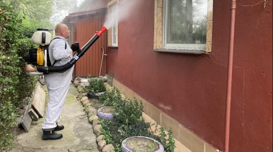 mężczyzna wykonuje oprysk budynku