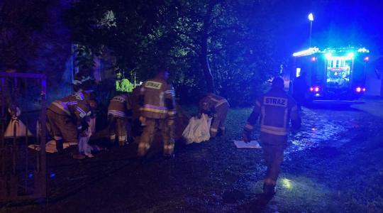 noc. strażacy układają worki z piaskiem.