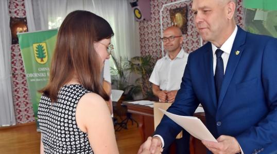 Absolwentka szkoły podstawowej odbiera nagrodę z rąk Burmistrza Arkadiusza Poprawy. W tle Dyrektor Szkoły Podstawowej w Pegowie Wojciech Wróbel. 