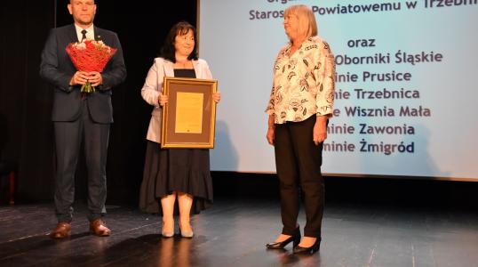 Burmistrz Obornik Śląskich Arkadiusz Poprawa i radna powiatowa Jadwiga Głodowska wręczają dyplom prezes Stowarzyszenia Oświatowego "Sowa" Marii Jaskólskiej